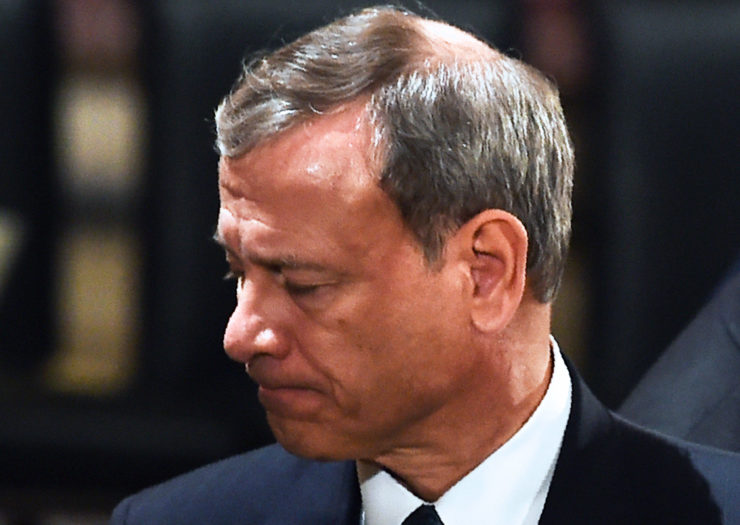 [Photo: U.S. Supreme Court Chief Justice John Roberts gives a grieving look during a ceremony.]