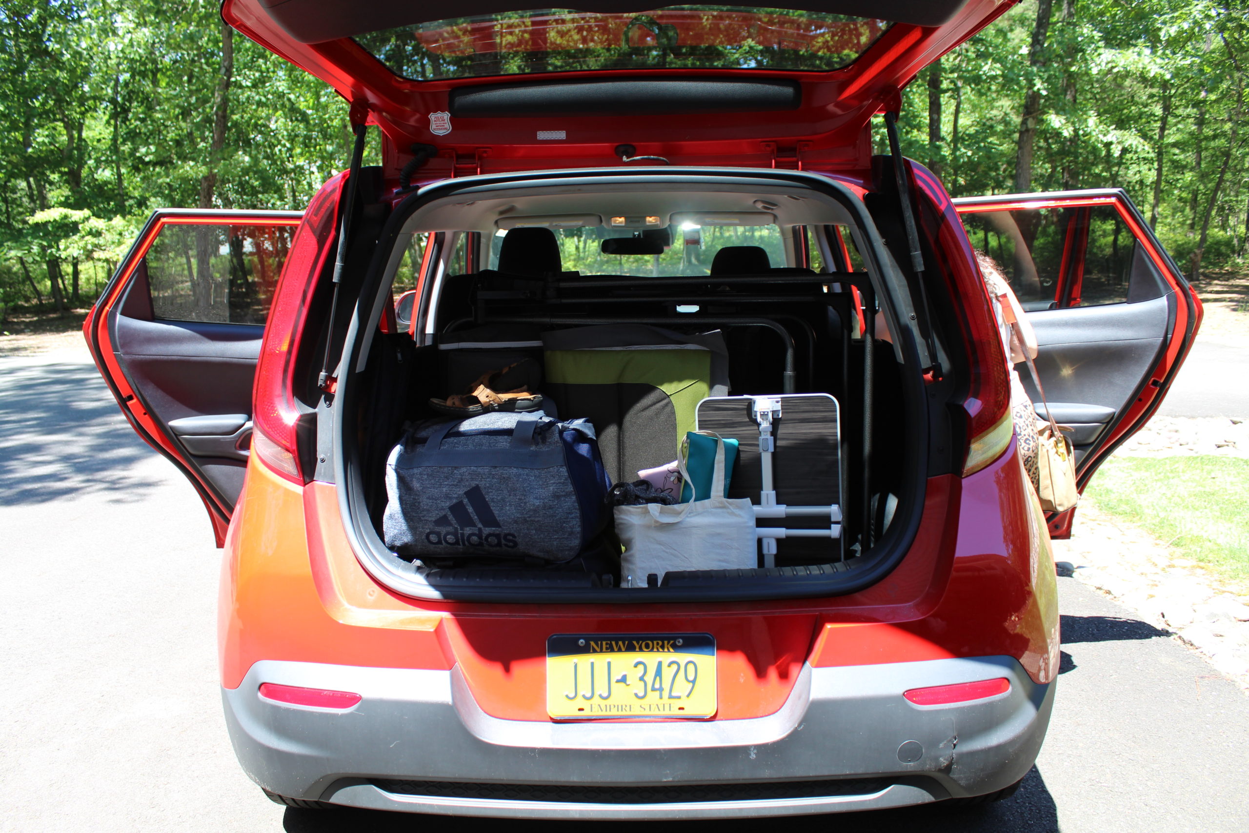 [Photo: A red hatchback car with the doors and trunk open, in the back, there is luggage and supplies.]